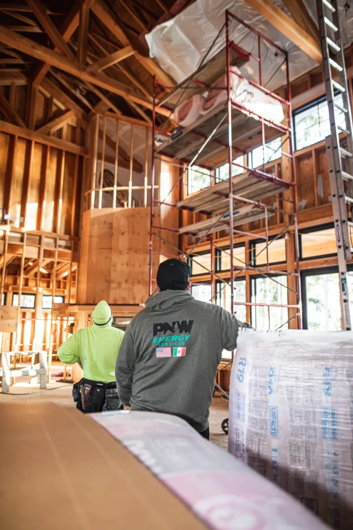 PNW Construction & Energy Services installing insulation in a tall vaulted ceiling during a new home build.